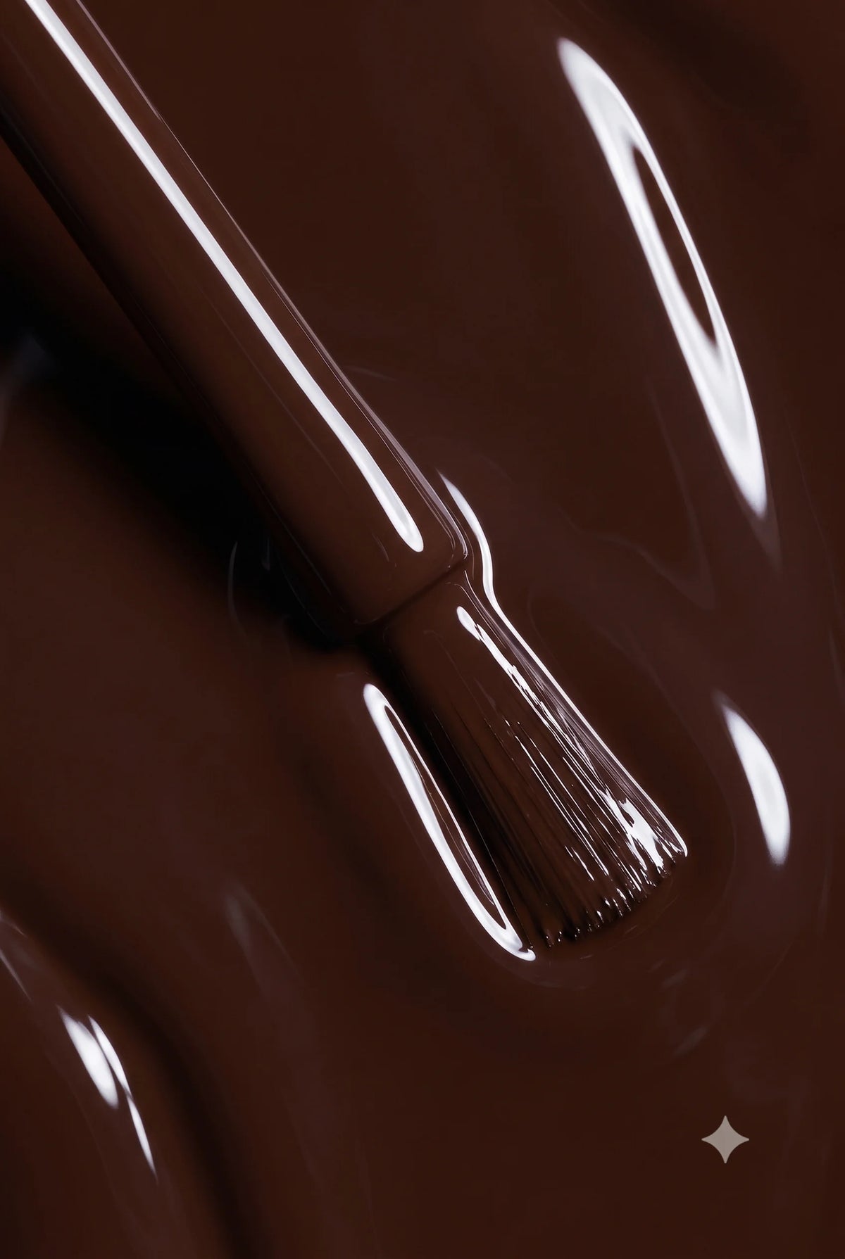 A glossy brown liquid, resembling melted chocolate or nail polish, with a brush stroke creating smooth highlights on a dark brown background.